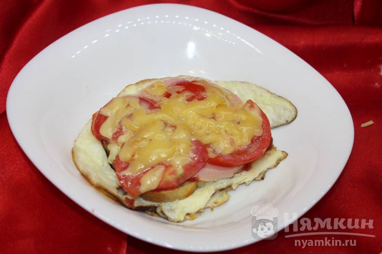 Омлет с хлебом, колбасой и помидорами на сковороде