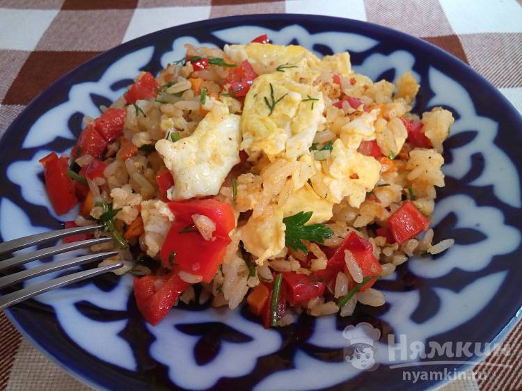 Жареный рис с яичницей и овощами на сковороде