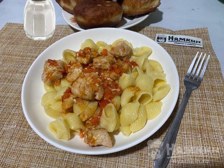 Тушеная свинина кусочками с луком, морковью и помидорами на сковороде